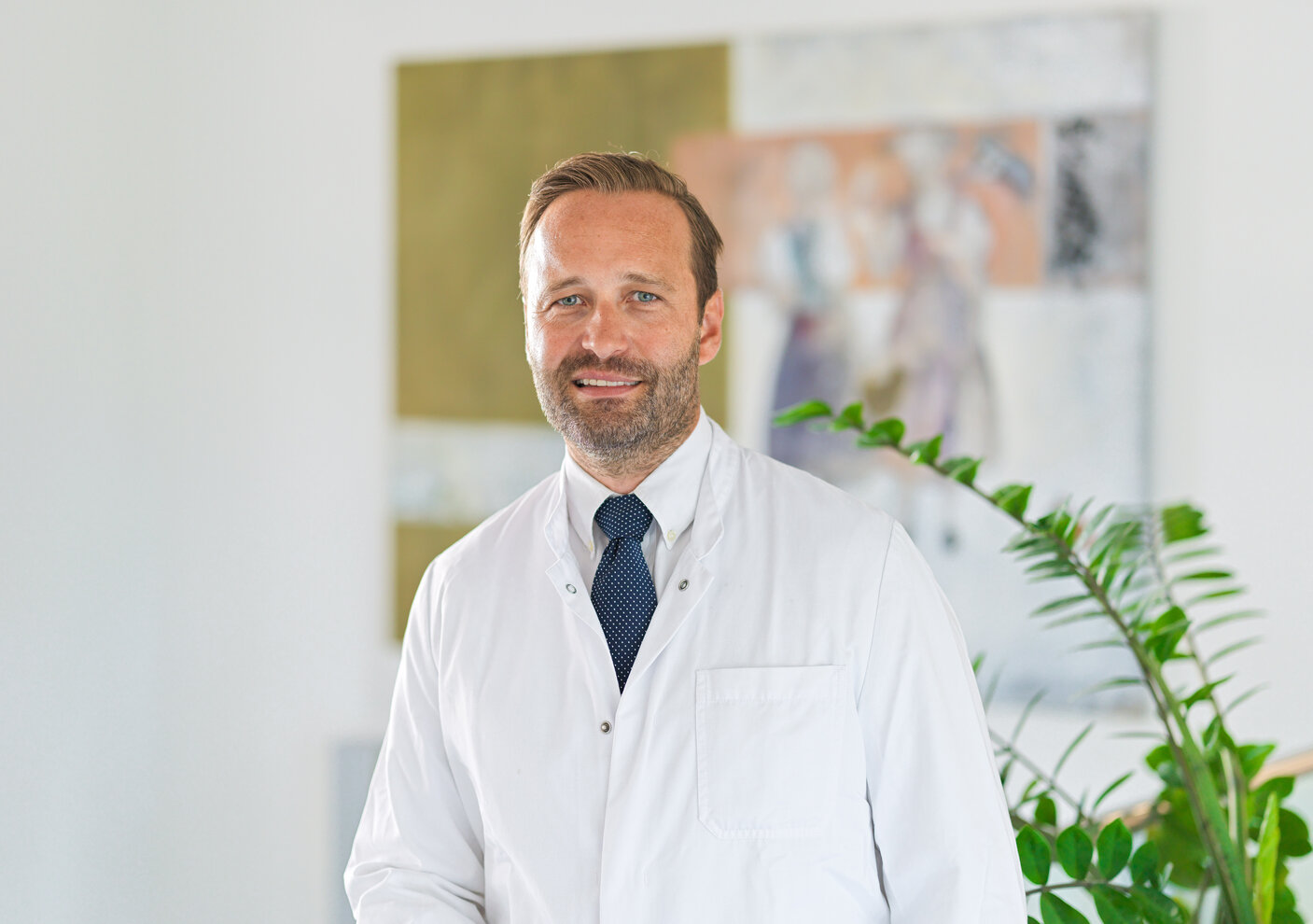 Dr. med. Peter Müller, Arzt, trägt einen weißen Kittel und eine Krawatte.